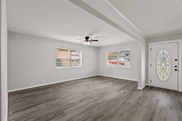 an empty room with wooden floor and windows