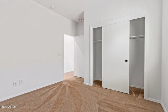 a view of an empty room with closet and a window