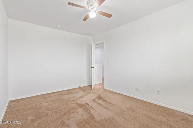 an empty room with closet and a chandelier fan