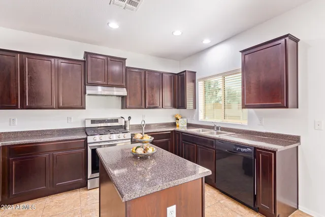 a kitchen with kitchen island granite countertop a sink stove and cabinets