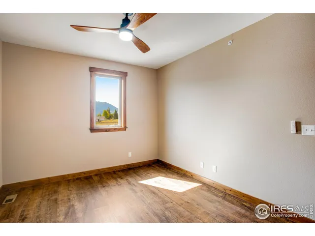 a view of empty room with wooden floor and ceiling fan