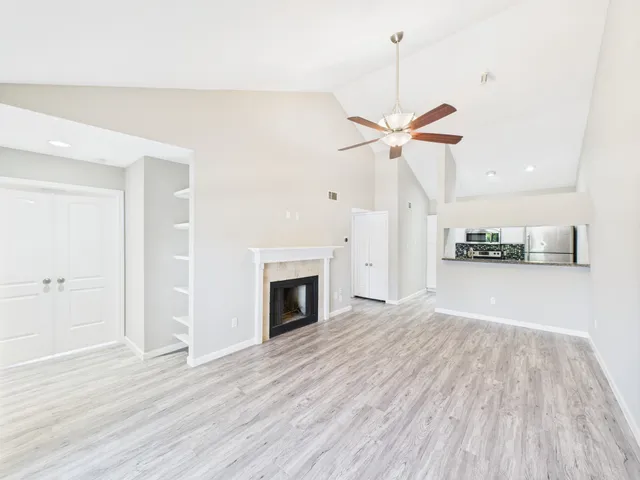 a view of a livingroom with a fireplace a ceiling fan and wooden floor