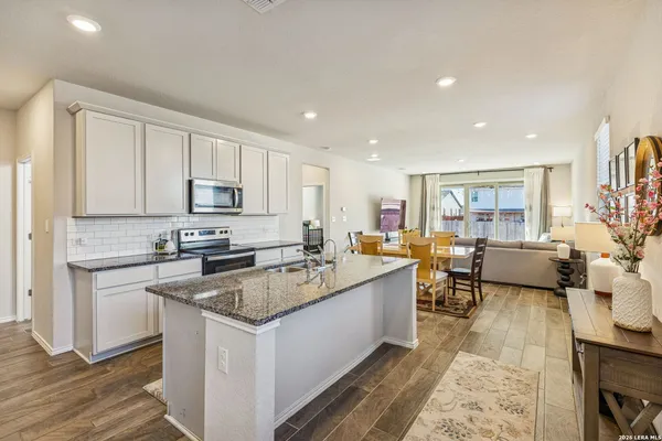 a large white kitchen with stainless steel appliances granite countertop a lot of counter space and a sink