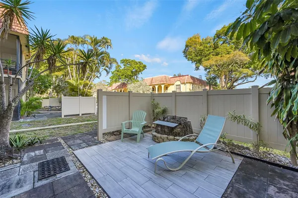 a view of backyard with seating space and trees in the background