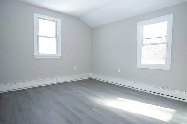 an empty room with wooden floor and windows