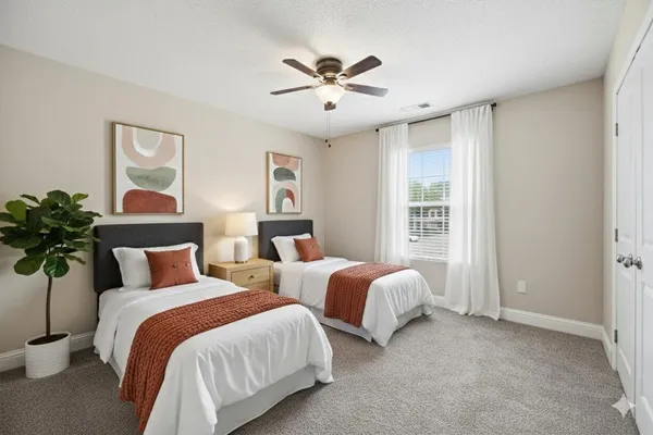 a bedroom with two separate beds and potted plant