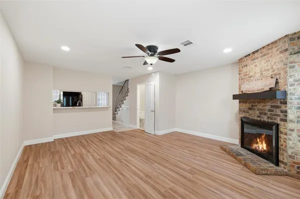 a view of a livingroom with a ceiling fan a fireplace and wooden floor