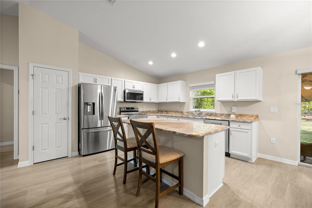 13131 Southwest 73rd Street Ocala, FL 34481 - Photo 7 of 30 a kitchen with stainless steel appliances a dining table chairs refrigerator and microwave