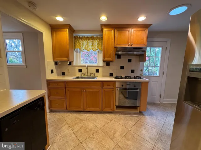 a kitchen with stainless steel appliances granite countertop a refrigerator a stove and a sink