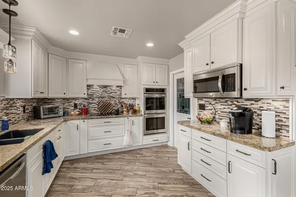 a kitchen with granite countertop white cabinets and stainless steel appliances