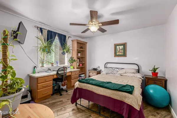 a bedroom with a bed table flowerpot and window