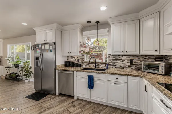 a kitchen with stainless steel appliances granite countertop a refrigerator a sink a stove a dining table and chairs