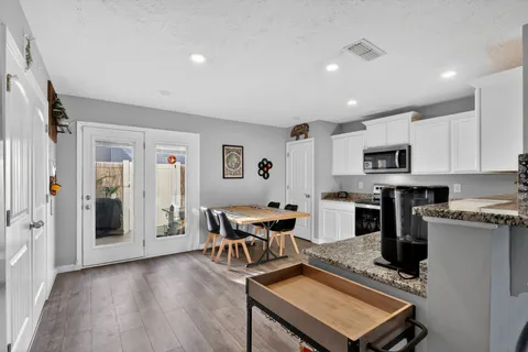 a living room with stainless steel appliances furniture and a wooden floor