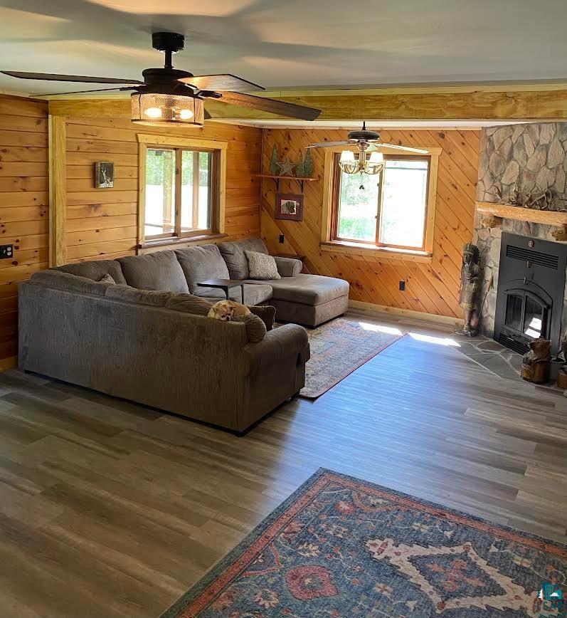 1896 Echo Trail Ely, MN 55731 - Photo 12 of 20 Living area featuring wood finished floors, a stone fireplace, ceiling fan, a chandelier, and wood walls