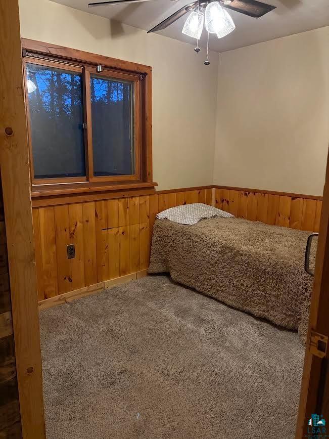 1896 Echo Trail Ely, MN 55731 - Photo 14 of 20 Bedroom with wood walls, carpet, ceiling fan, and a wainscoted wall