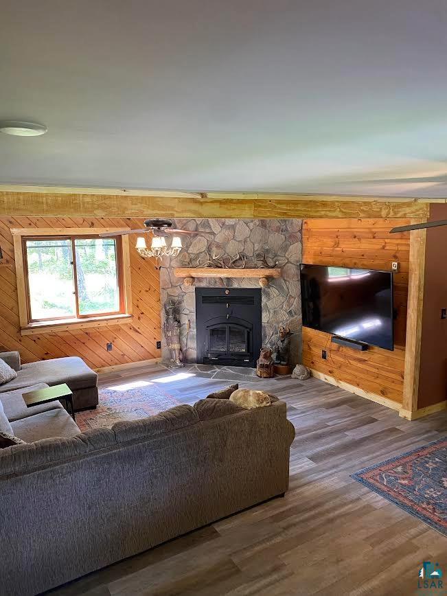 1896 Echo Trail Ely, MN 55731 - Photo 15 of 20 Living area with wood walls, wood finished floors, a chandelier, and a stone fireplace