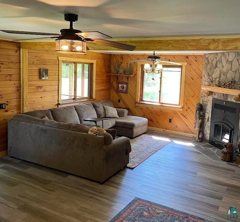 1896 Echo Trail Ely, MN 55731 - Photo 9 of 20 Living area with plenty of natural light, wood finished floors, a fireplace, wooden walls, and a ceiling fan