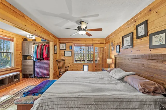 a bedroom with a bed a dresser and a large window