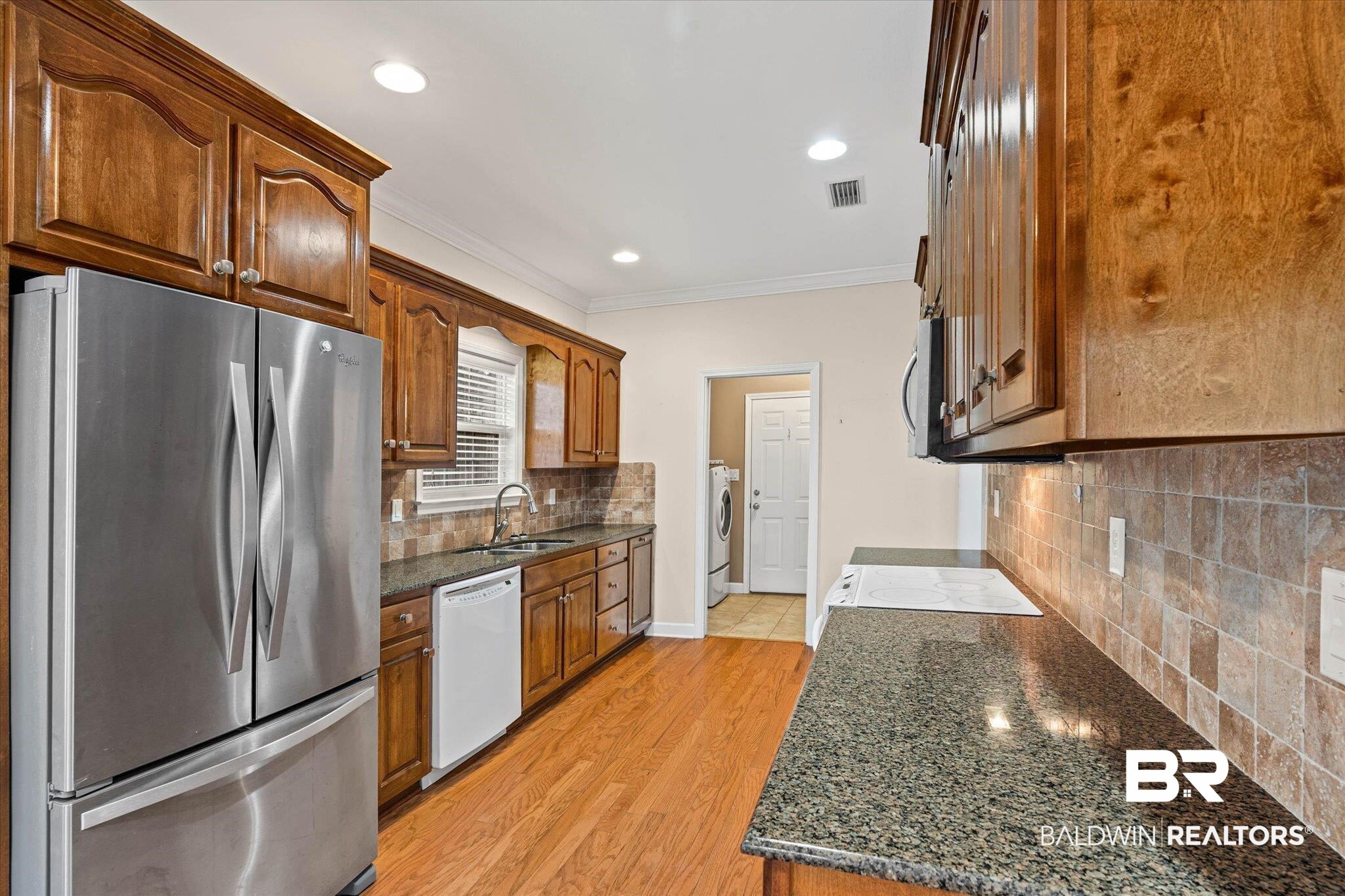 1003 Weatherby Street South Saraland, AL 36571 - Photo 16 of 31 Kitchen with stainless steel appliances, dark stone countertops, ornamental molding, light wood-style floors, and tasteful backsplash