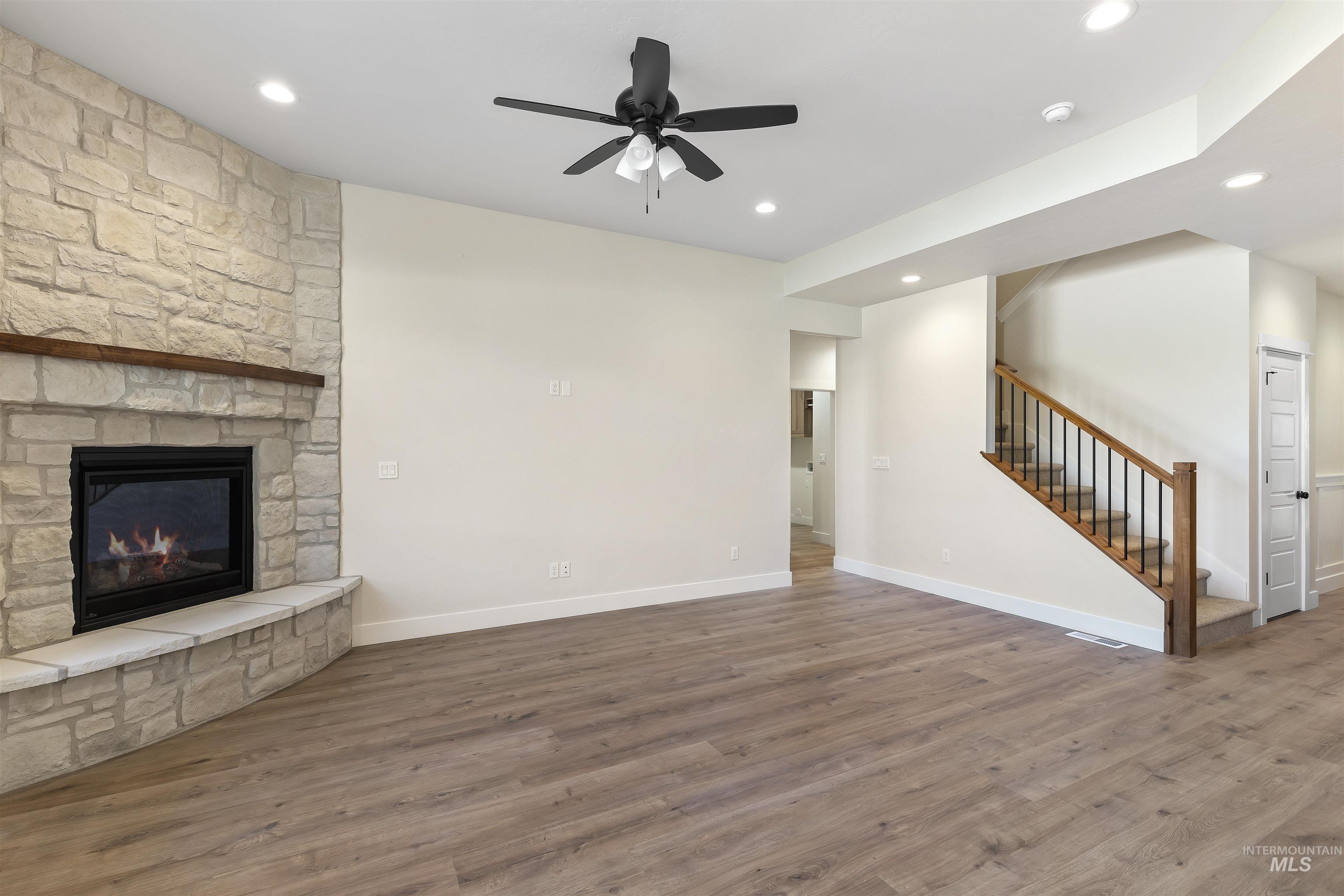 3501 South El Rio Avenue Boise, ID 83709 - Photo 11 of 31 Unfurnished living room featuring a ceiling fan, dark wood-style flooring, a stone fireplace, and recessed lighting
