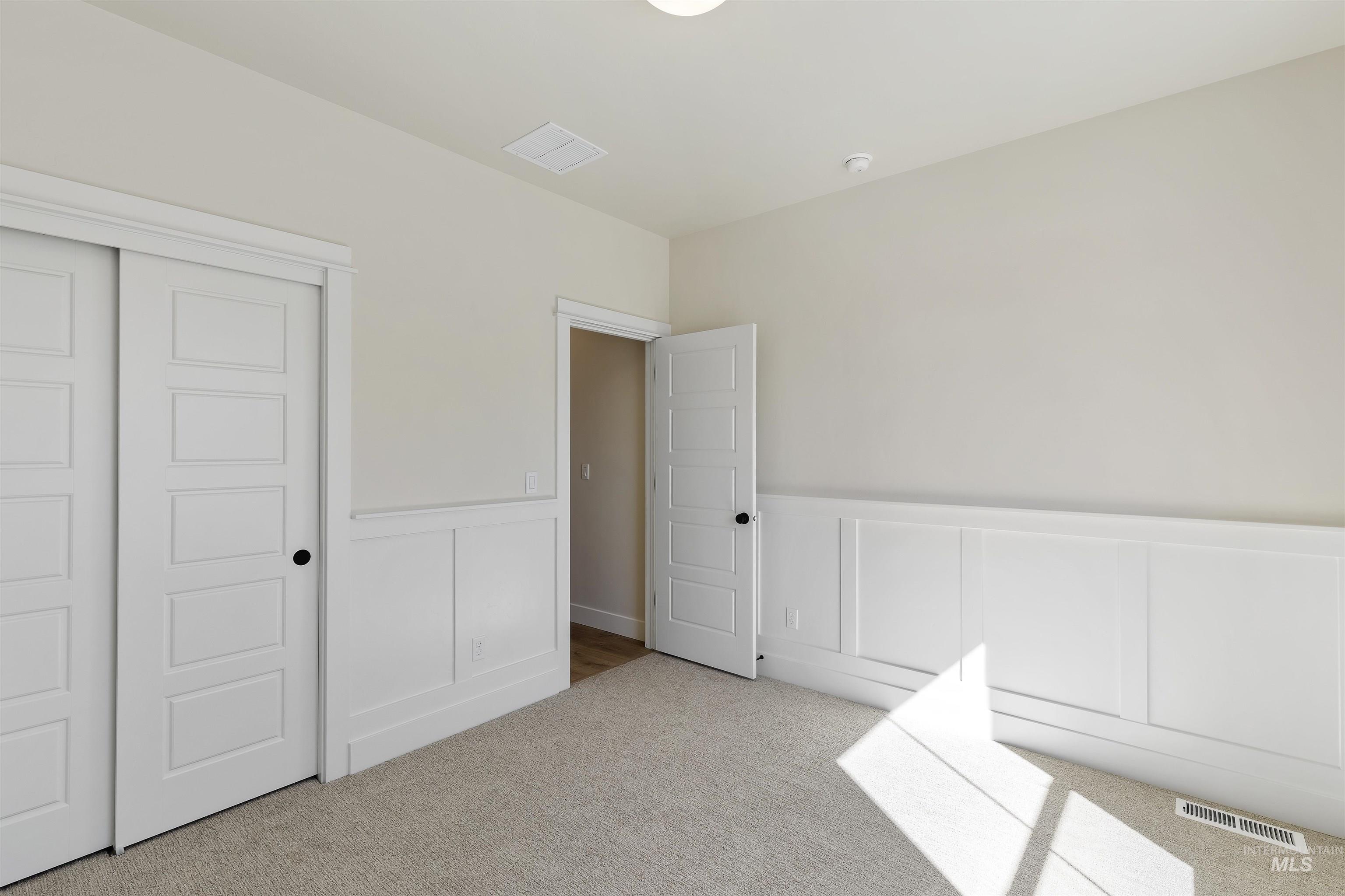 3501 South El Rio Avenue Boise, ID 83709 - Photo 24 of 31 Unfurnished bedroom featuring a decorative wall, a wainscoted wall, light carpet, and a closet