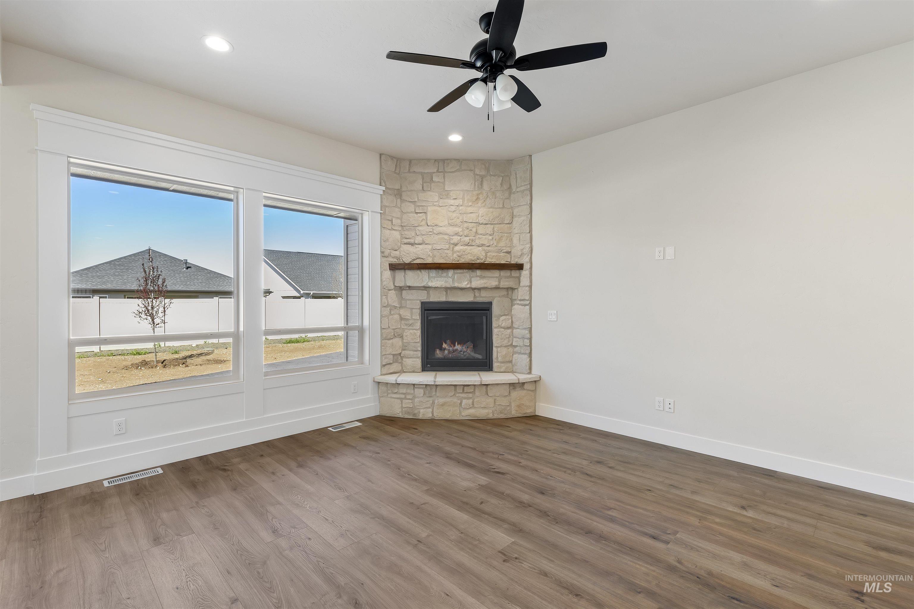 3501 South El Rio Avenue Boise, ID 83709 - Photo 9 of 31 Unfurnished living room with a ceiling fan, dark wood-style floors, recessed lighting, and a fireplace