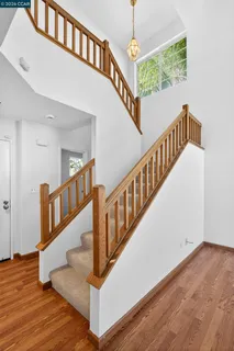 a view of staircase with lots of frames on wall and wooden floor