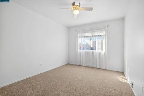 an empty room with a window and ceiling fan