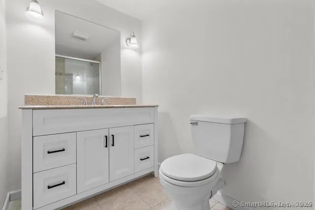 a bathroom with a granite countertop toilet sink and mirror