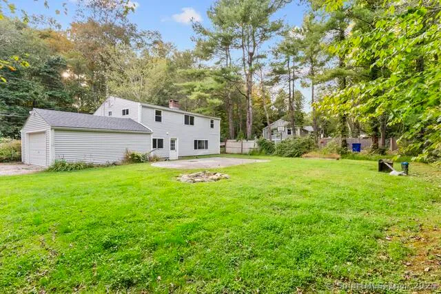 a view of a white house with a big yard and large tree