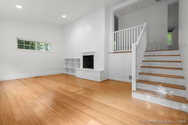 a view of empty room with stairs and wooden floor