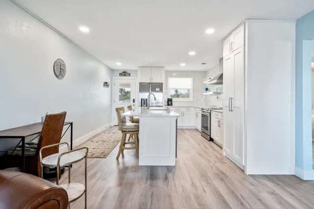 a kitchen with a table chairs wooden floors and a view of living room