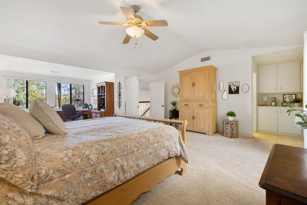 a spacious bedroom with a bed a ceiling fan and a dresser