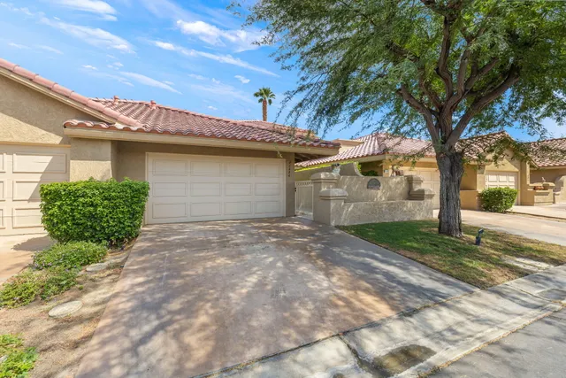 a view of a white house with a large tree