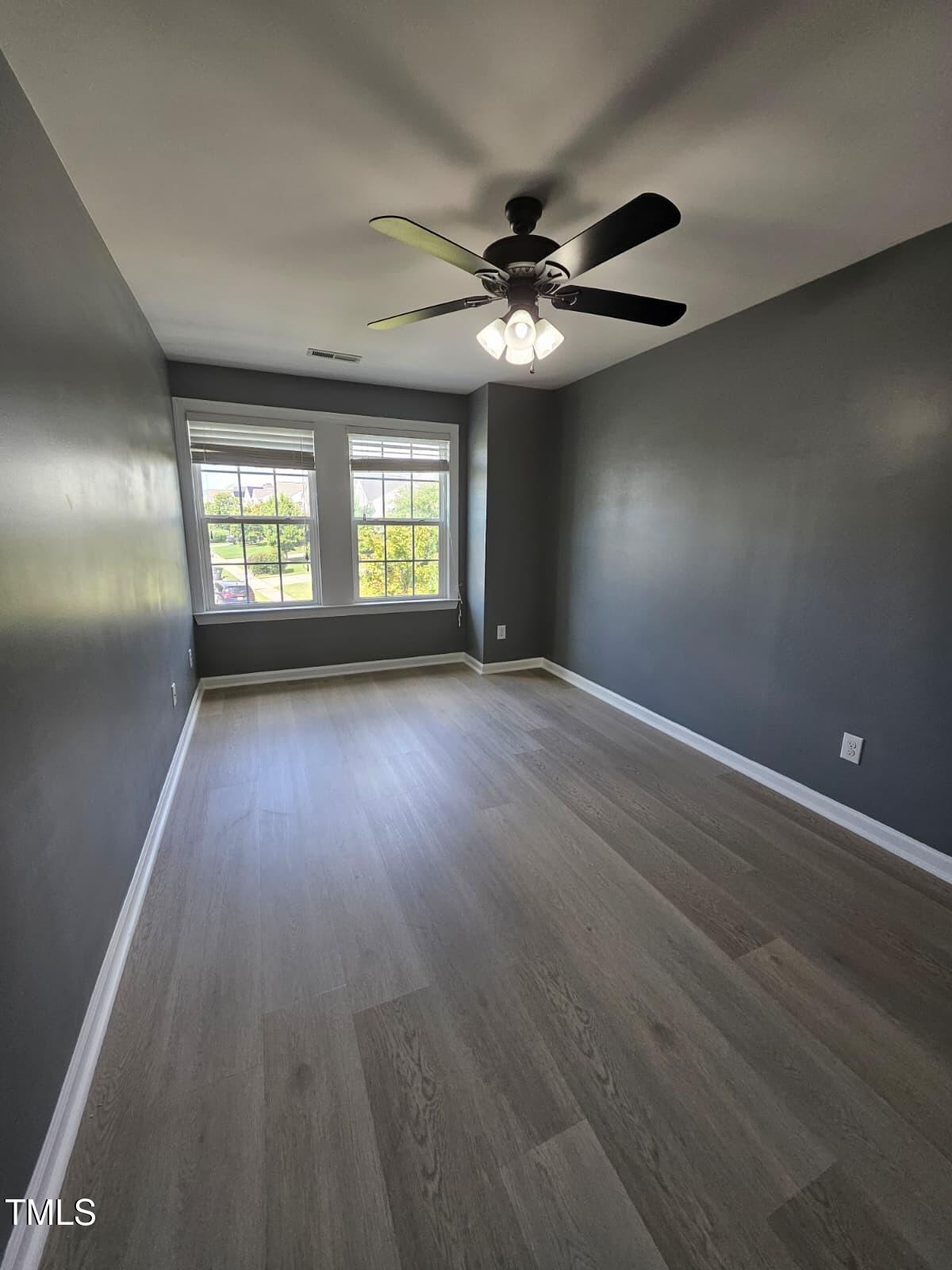 2205 Kirkhaven Road Morrisville, NC 27560 - Photo 18 of 36 an empty room with wooden floor chandelier fan and windows