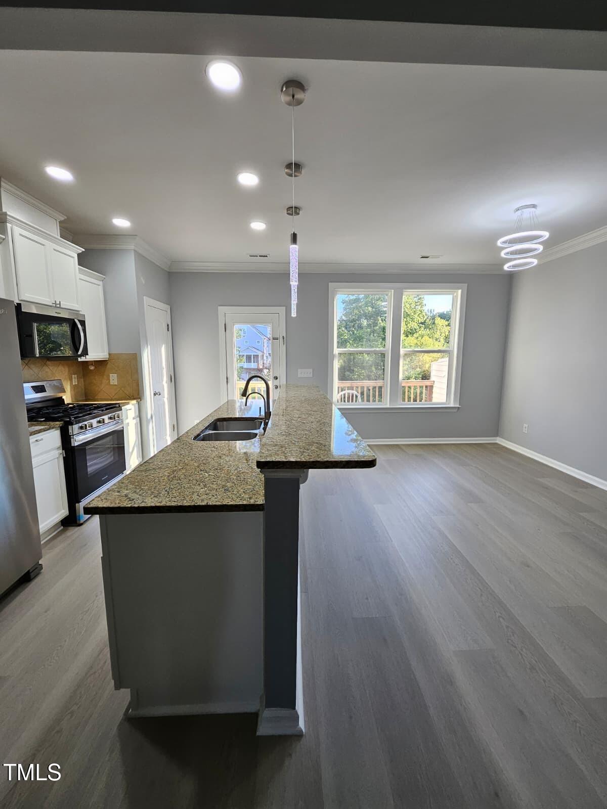 2205 Kirkhaven Road Morrisville, NC 27560 - Photo 7 of 36 a view of a kitchen with kitchen island wooden floors and stainless steel appliances