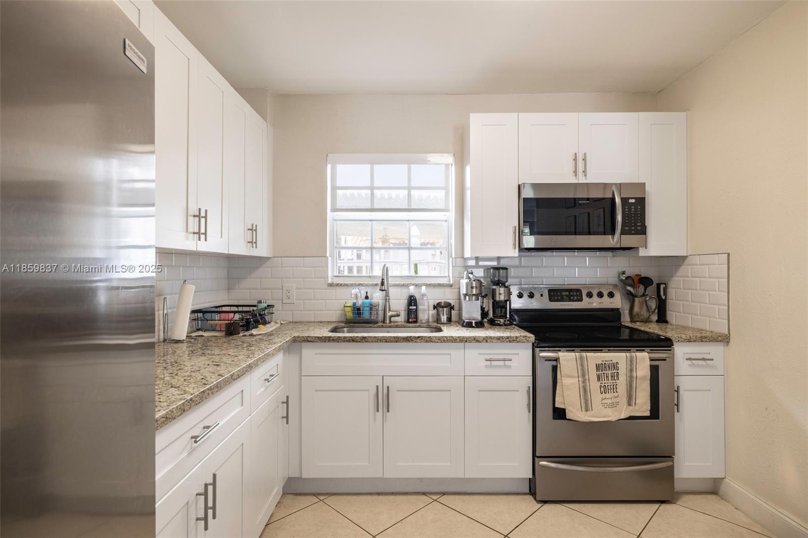 2928 Southwest 5th Street, Unit C Miami, FL 33135 - Photo 5 of 15 a kitchen with stainless steel appliances granite countertop a stove top oven a sink a microwave and cabinets