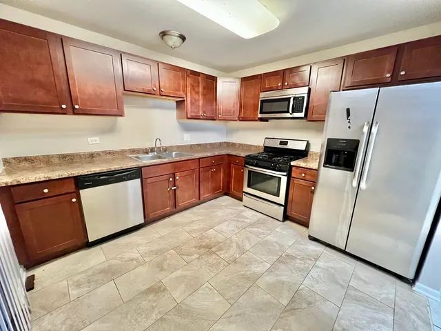 a kitchen with stainless steel appliances granite countertop a stove a sink dishwasher a refrigerator and a microwave