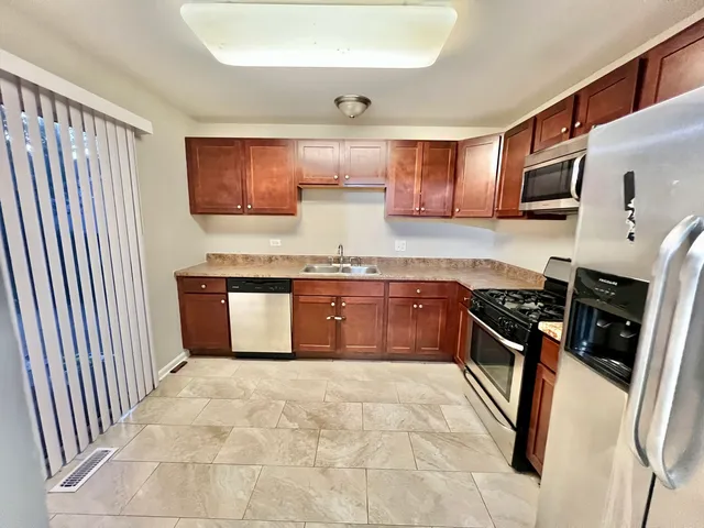 a kitchen with stainless steel appliances granite countertop a stove a sink and a refrigerator