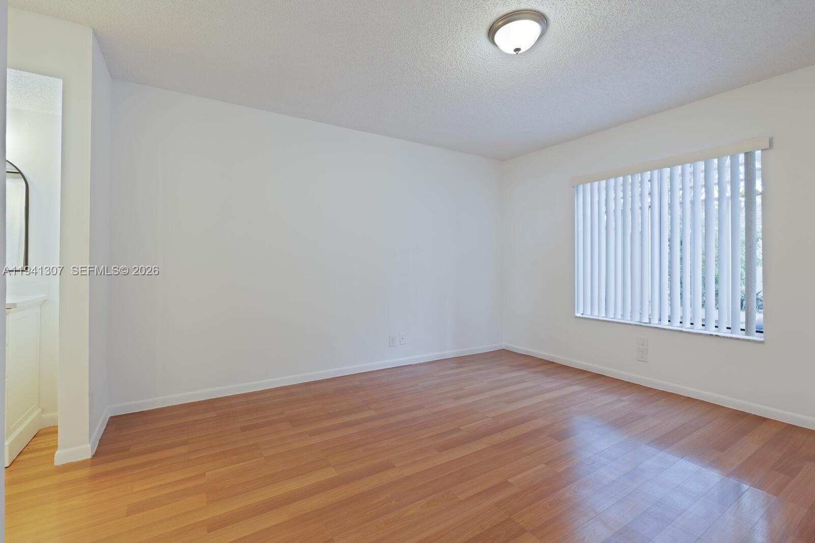 9500 Southwest 140th Court, Unit 9500 Miami, FL 33186 - Photo 11 of 21 an empty room with wooden floor and windows