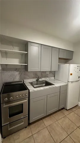 a kitchen with a sink a stove top oven and cabinets