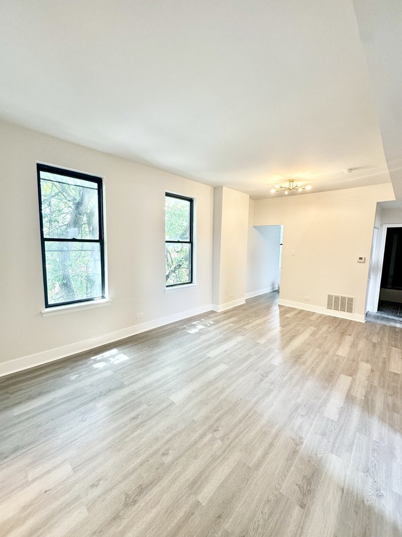3008 West 23rd Street, Unit 2B Chicago, IL 60623 - Photo 6 of 10 an empty room with wooden floor and windows