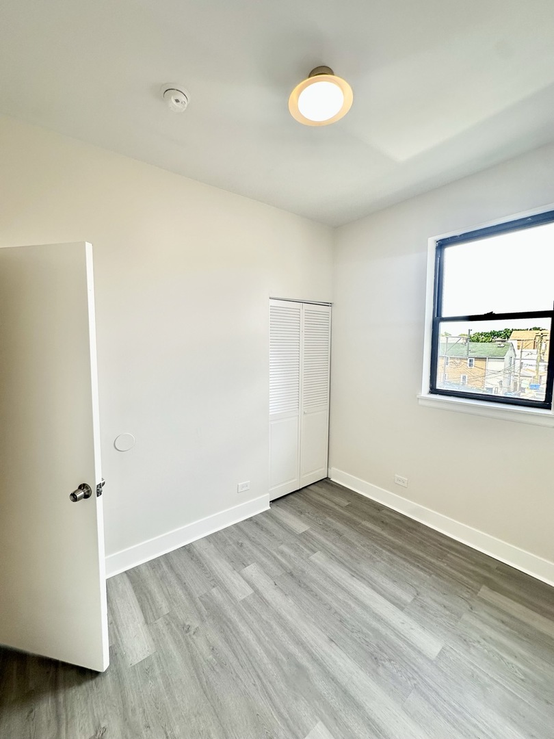 3008 West 23rd Street, Unit 2B Chicago, IL 60623 - Photo 7 of 10 an empty room with wooden floor and windows