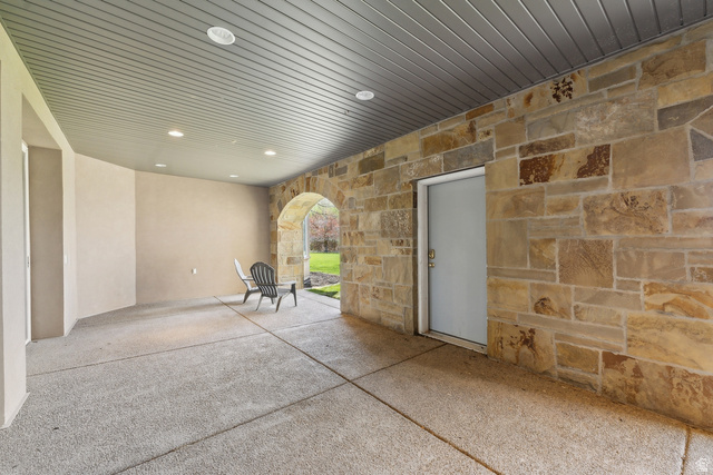 1714 Ridge Point Drive Bountiful, UT 84010 - Photo 93 of 132 Expansive covered patio featuring a stone accent wall, arched stone entryway, recessed lighting, and a textured concrete surface