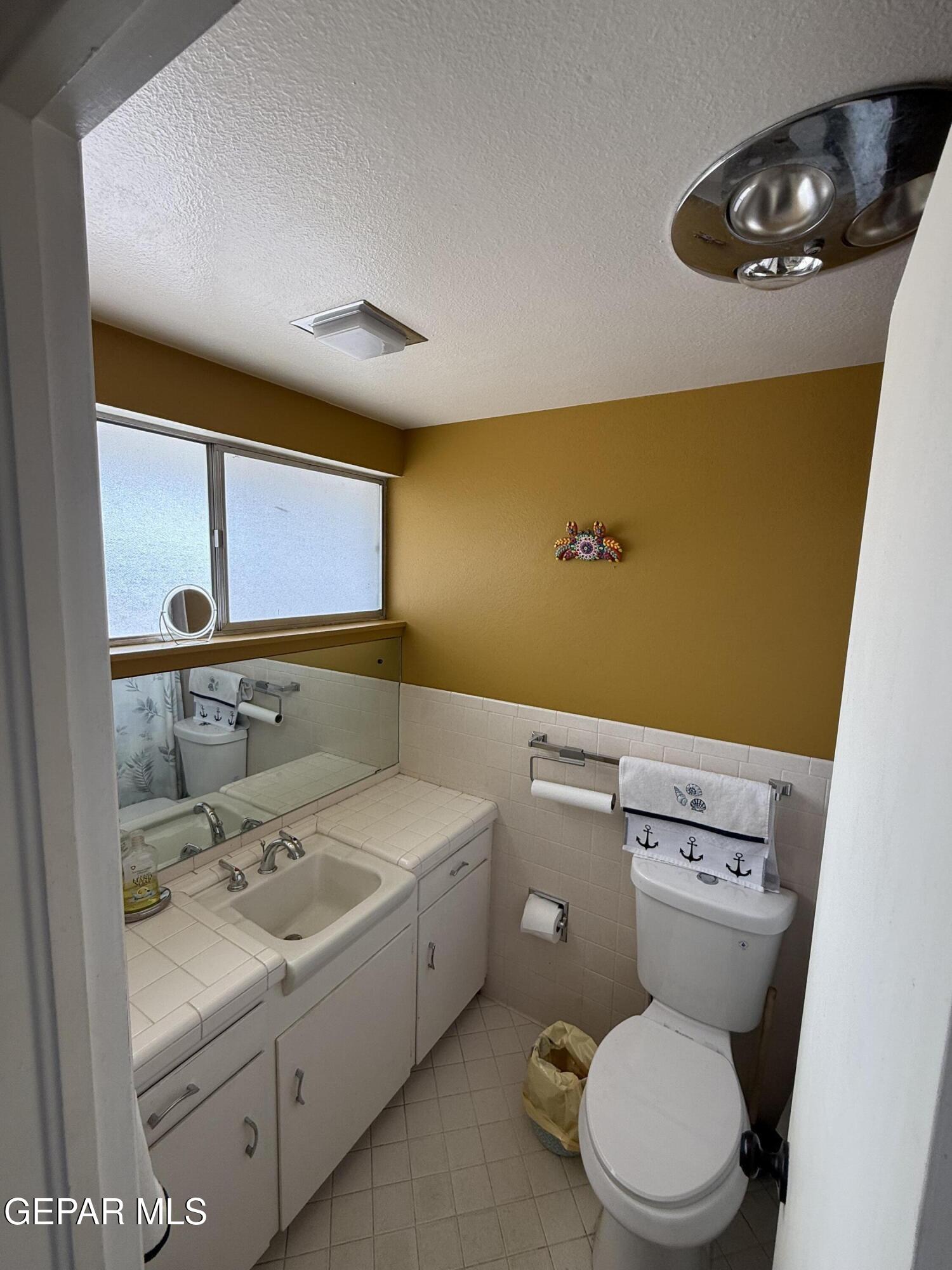 313 Clairemont Road El Paso, TX 79912 - Photo 12 of 34 a bathroom with a sink a toilet and mirror