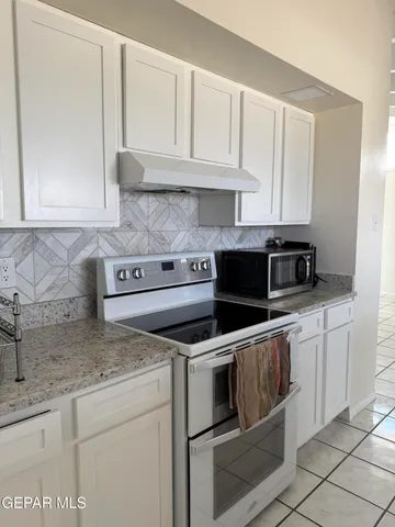 a kitchen with granite countertop white cabinets and stainless steel appliances