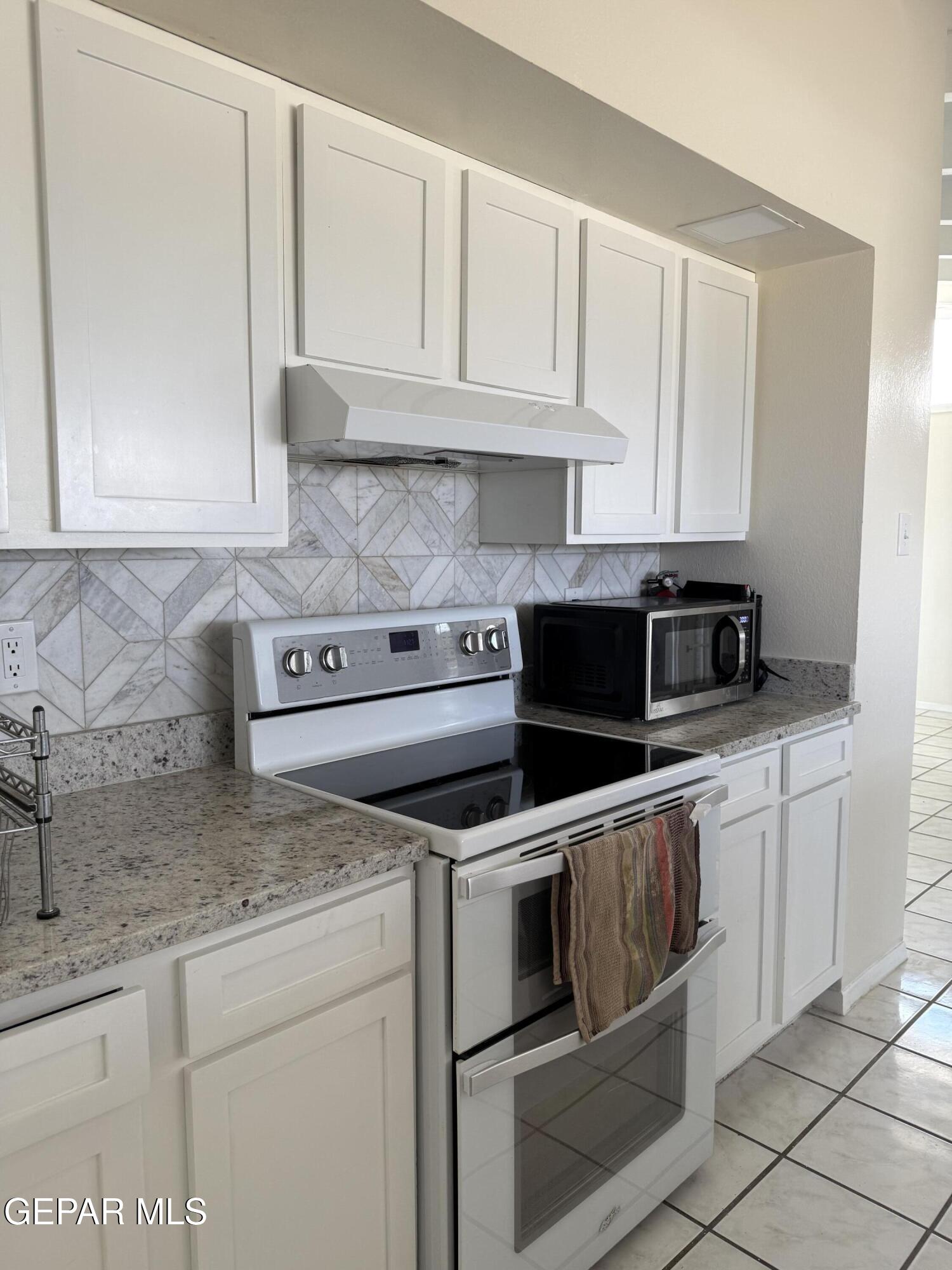 313 Clairemont Road El Paso, TX 79912 - Photo 19 of 34 a kitchen with granite countertop white cabinets and stainless steel appliances