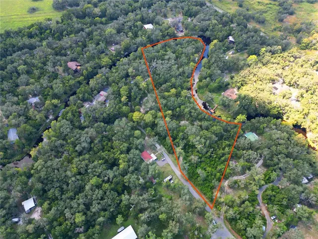 an aerial view of residential houses with outdoor space and trees