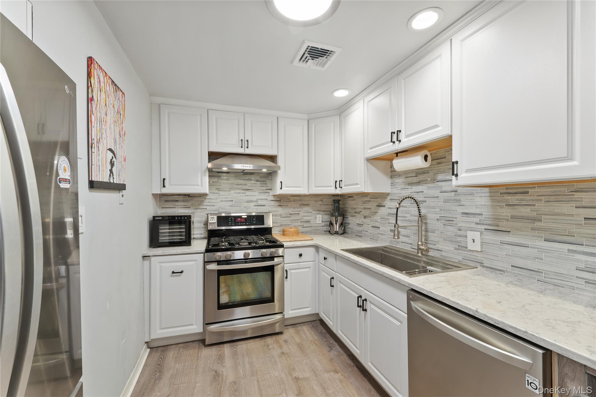 147 I U Willets Road Albertson, NY 11507 - Photo 8 of 14 a kitchen with white cabinets stainless steel appliances and sink