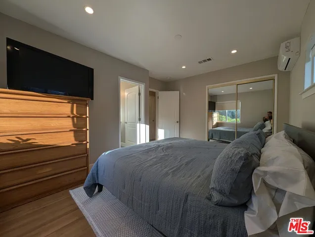 a bedroom with a bed and a flat tv screen on dresser